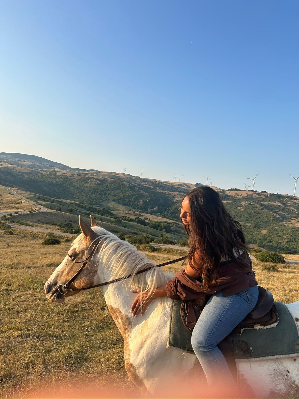 Ragazza in sella a un cavallo bianco al tramonto